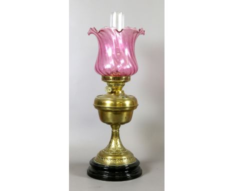 A Victorian brass based oil lamp with cranberry glass shade