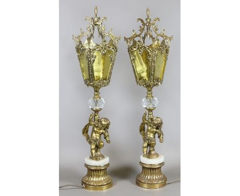 A very ornate pair of brass table lamps with amber glass lantern shades, the pedestals adorned with puti over marble and gilt