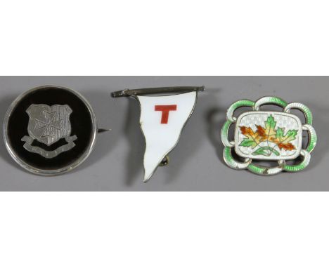 A silver and tortoise shell brooch and two enamel badges.