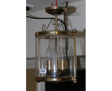 A cylinder shaped brass and clear glass hall lantern.