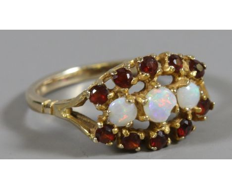 A ladies 9ct gold ring set with three opals surrounded by two bands of garnets, size L 1/2.