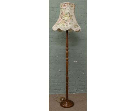 A turned oak standard lamp with floral fabric shade.