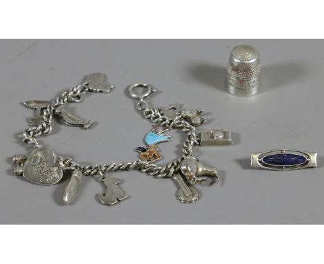 A silver charm bracelet with enamel charms, a silver and enamel brooch by Charles Horner and a silver thimble. 