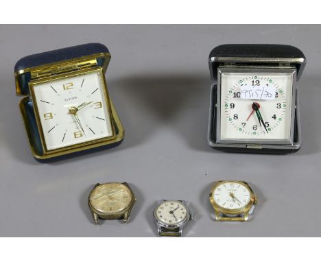 Three manual watch heads and two folding bedside clocks.