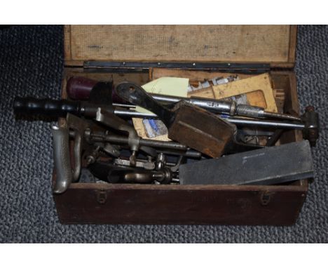 A wooden box containing an assortment of tools, including torque wrench, hand planes, sharpening stone and bit and brace etc.