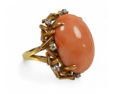 A 14k gold, diamond and coral ring, circa 1960's, the pale pink oval cabochon coral approx 19 by 12mm, surrounded by eight sm