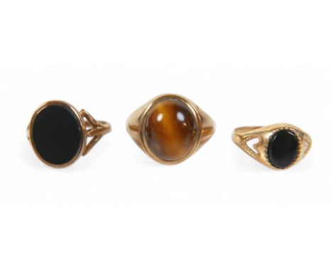 A group of three 9ct gold signet rings, one set with a cabochon tiger's eye, size P/Q, and two set with black onyx, sizes J/K