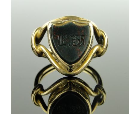 An unusual Victorian unmarked gold seal ring,
the shield shaped bloodstone panel having a hinged compartment, setting height 