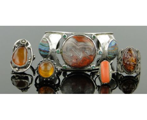 A hardstone set bangle,
3 silver and amber rings and a coral ring, (5).