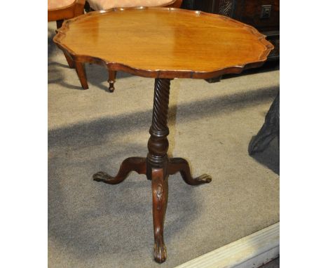 A mahogany tilt-top tea table
on carved tripod base, 25" across.