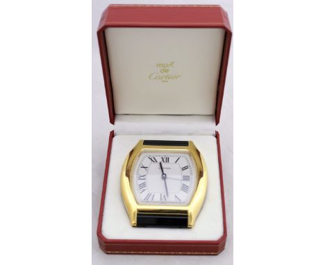 A boxed Must de Cartier travel clock in the form of a wristwatch face, the white enamel dial set with Roman numerals and insc