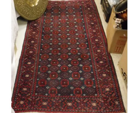 A Beluch rug, the central panel set with repeating medallions and stylised floral design on a navy ground within a stepped re