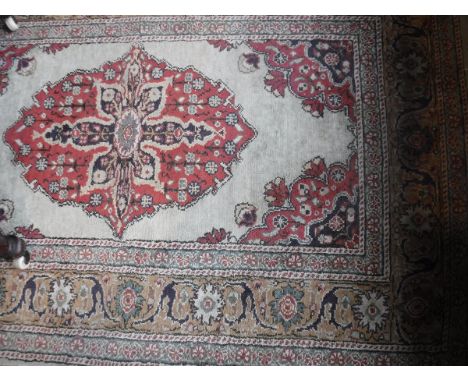 A Turkish rug, the central panel set with floral decorated medallion on a cream ground within a stepped green, terracotta and