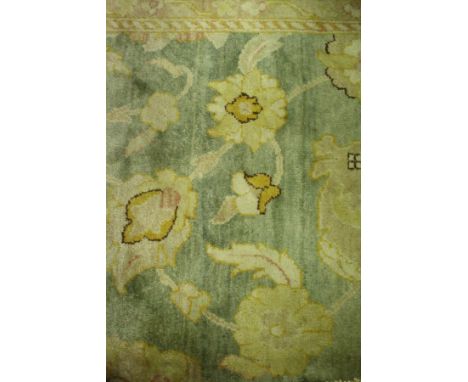 A Ziegler design carpet, the central panel with all over floral decoration, within a stepped mustard and green floral decorat