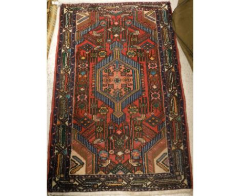 A Caucasian rug, the central panel set with lozenge shaped medallion on a red geometric patterened ground within in a stepped