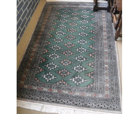 A Pakistan rug, the central panel set with repeating medallions on a green ground within a stepped mushroom, salmon pink and 