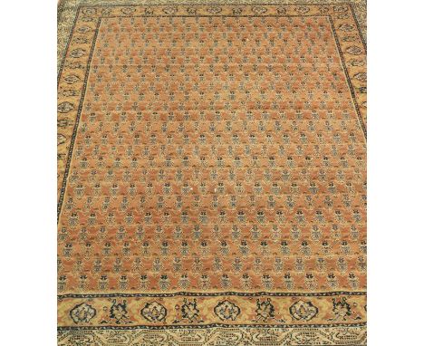 A modern Persian style rug, the central panel set with allover repeating design on a salmon pink ground within a stepped salm