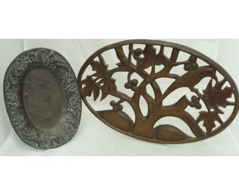An embossed copper oval dish with foliate and fruit decoration in the Arts and Crafts manner, together with a carved wooden A