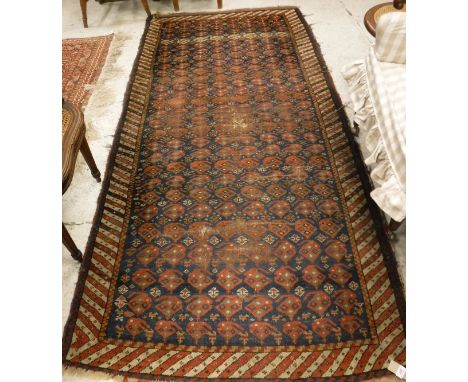 A Persian carpet, the central panel set with repeating hook motifs on a navy ground within a stepped striped cream and red bo