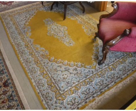 A Persian style rug, the central panel set with floral decorated medallion on a mustard ground within a mustard, duck egg blu