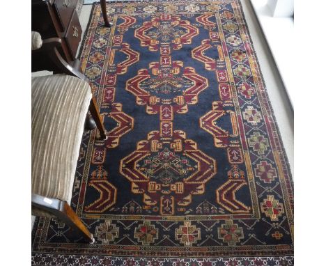 An Afghan triple medallion rug with brocade ends, the central panel set with three medallions on a dark blue ground within a 