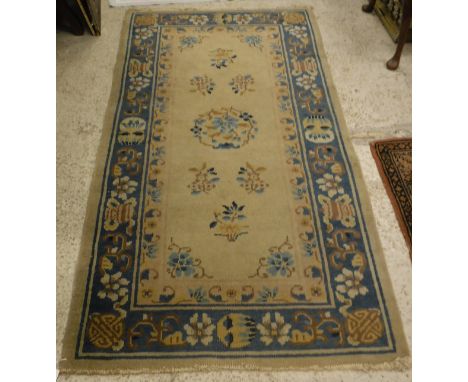 A Chinese rug, the central panel set with floral sprays on a fawn ground, within a pink, fawn and blue floral decorated and s