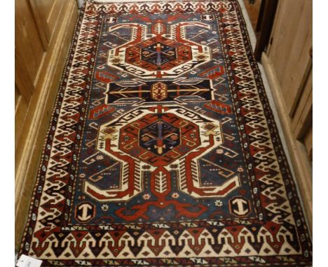 A Shirvan rug, the central panel set with two medallions on a midnight blue ground with geometric pattern within a stepped bl