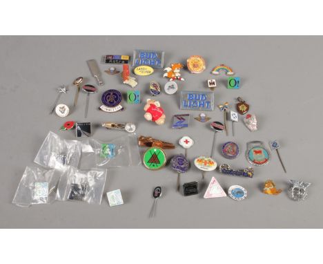 A collection of assorted badges and charms, including enamel examples.  