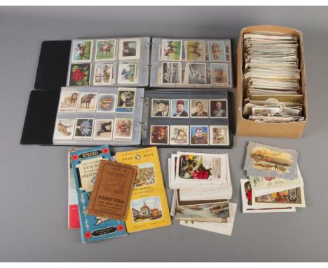 A large quantity of vintage postcards along with two albums of cigarette cards.  