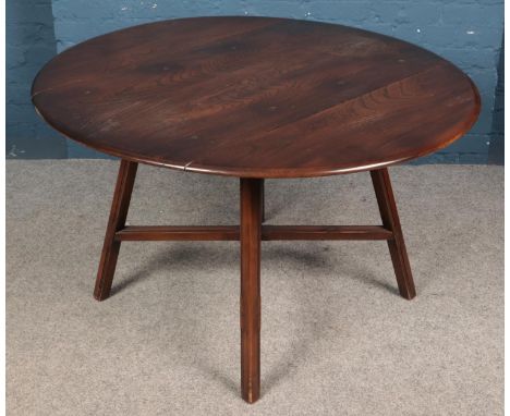 An Ercol dark elm drop leaf dining table, with central cross stretcher. Height: 72cm, Width: 113cm, Depth: 65/117cm.  