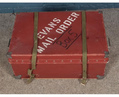 A red luggage trunk bearing Evans Mail Order to top.  