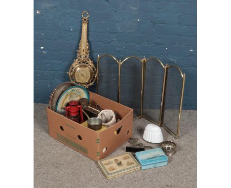 A box of metalwares. Includes brass barometer, folding spark guard, vintage tins, enamel jelly mould etc.  