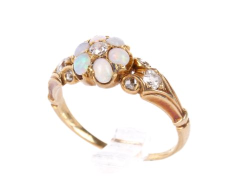 A Victorian gold and opal cluster ring. The petals of small opals of various colours centred with a diamond and with further 