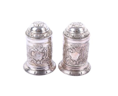 A pair of Victorian silver cylindrical pepperettes. With repousse decoration of flowers and leaves, raised on a spread foot, 