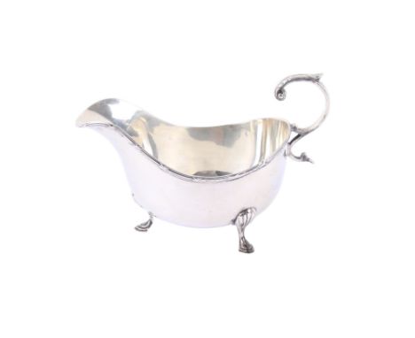 A George V silver sauce boat. Maker Walker & Hall, Sheffield 1927, having an engraved scroll handle and three stepped feet, 1
