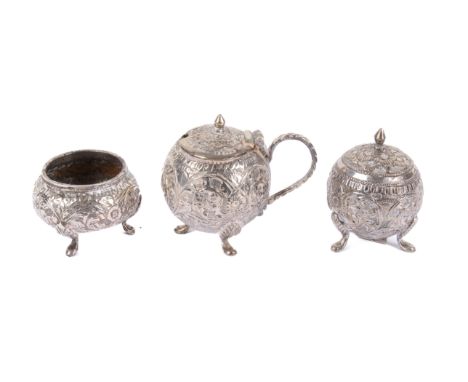 A Persian white metal three piece cruet set. Decorated with dense scrolling leaves, raised on out turned feet, marked to unde