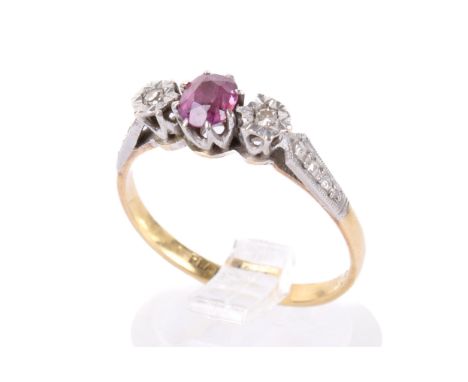 A yellow and white metal three stone dress ring. Set with one oval faceted ruby of 0.35 carats approximately and two single c