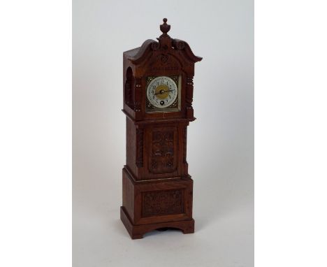 A late 19th century/early 20th century oak miniature longcase clock with square dial and ring of Arabic numerals in a carved 