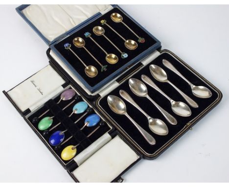 A cased set of six silver gilt coffee spoons, each with enamelled floral terminal, together with a cased set of six silver an