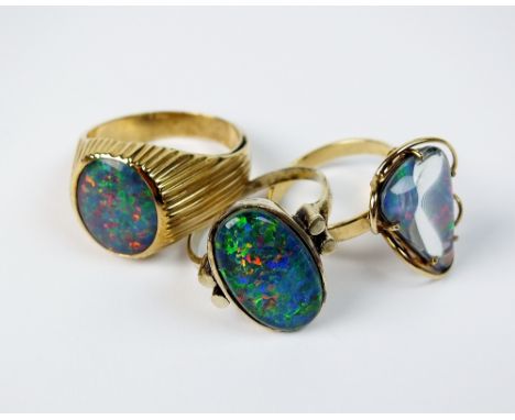 Two oval opal triplet dress rings, stamped '9ct' and '375', together with a triangular opal triplet dress ring (3)