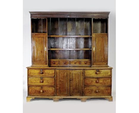 An early 19th century oak high dresser the rack with three central shelves over four short drawers flanked by an open cabinet