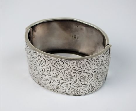 A Victorian silver hinged bangle, with engraved foliate scrolling decoration, hallmarked Chester 1883, weight 35gms, (at faul