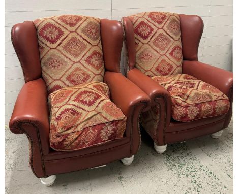 A pair of brown leather wing back arm chairs with Aztec style upholstery to seat and back cushions 