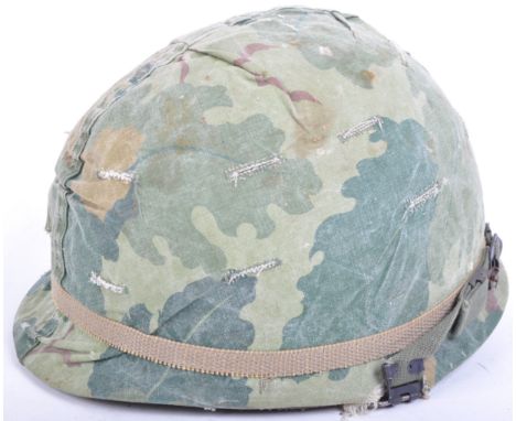 An original Vietnam War era US United States Army M1 camo helmet. The helmet having a steel outer shell with a hard-hat type 