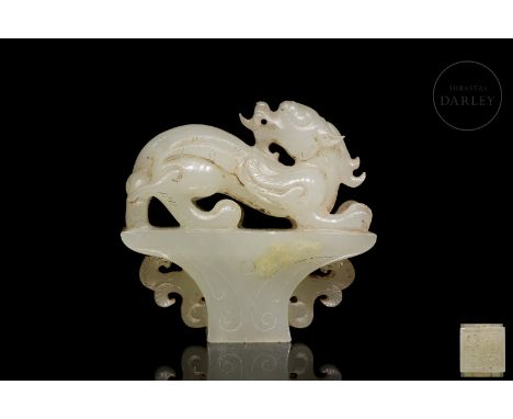 Light-coloured jade with subtle ochre and reddish flecks. The base has a trapezoidal structure, decorated with scrolls and in