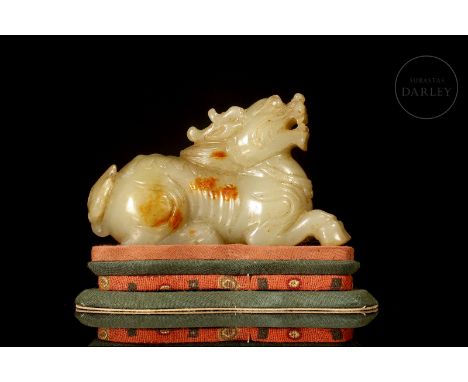 A light-coloured carved jade with reddish flecks. It depicts a beast, known in Chinese mythology as ‘Qilin’, reclining on its