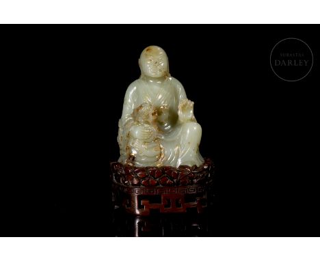 A beautifully carved jade of a soft, greenish hue, with reddish flecks and traces of gold leaf. It shows the image of a seate