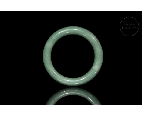 Jade of a soft greenish hue, carved in the shape of a bracelet, with rounded edges and a smooth surface. The shape is rigid a
