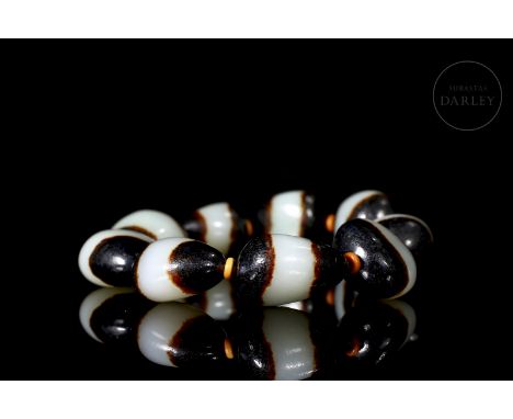 Jade carved in the form of nine small beads. It has a beautiful pattern of coloured stripes: white in the centre, brown on th