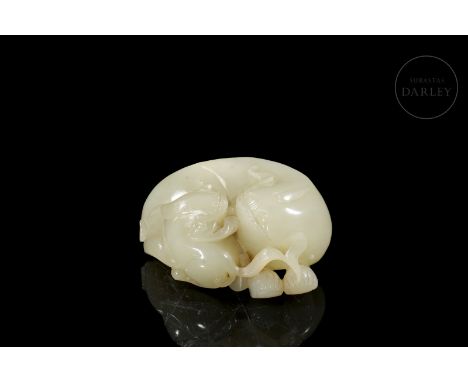 Carved white jade. It shows a crouching mythical beast, with its body tucked up, tucking in its young calf. They have a seren